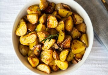 a white bowl filled with cooked potatoes on top of a table